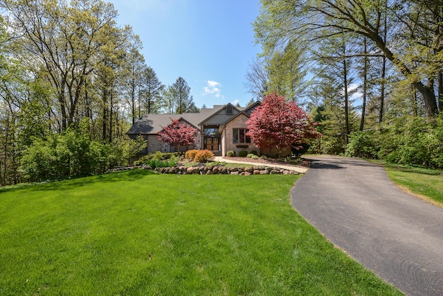 view of front of house featuring a front yard, brick siding, and driveway