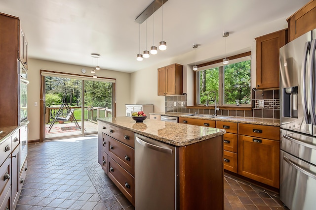 kitchen featuring stainless steel appliances, a sink, brown cabinetry, and decorative backsplash