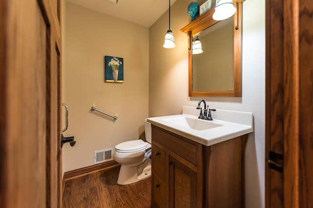 bathroom with wood finished floors, toilet, vanity, and baseboards