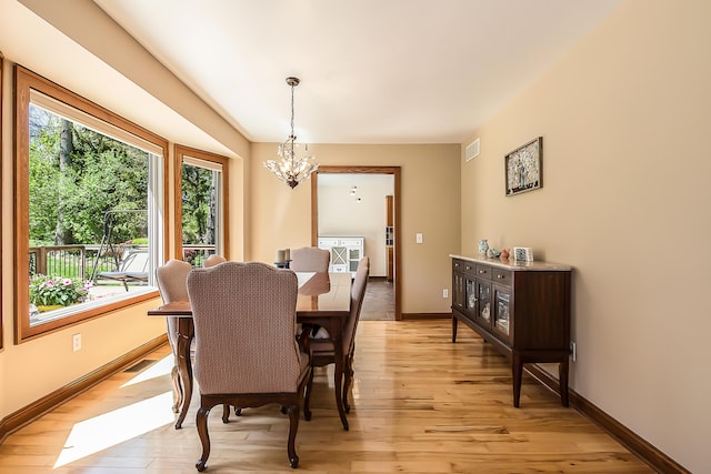 dining room with a chandelier, light wood finished floors, and baseboards
