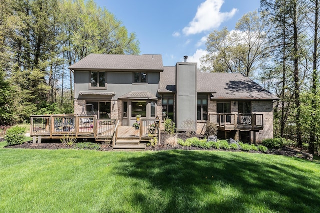 back of property with a wooden deck, a chimney, a yard, and brick siding