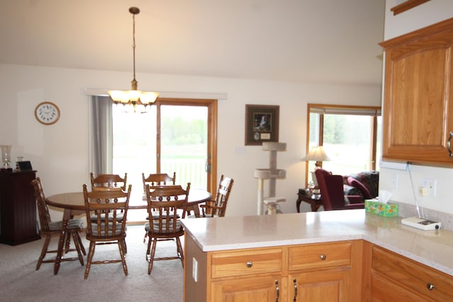 kitchen featuring a peninsula, light countertops, a chandelier, and plenty of natural light