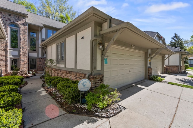 42036 Saratoga Cir, Canton, MI 48187 - view of home's exterior with brick siding, a garage, concrete driveway, stucco siding, and a shingled roof