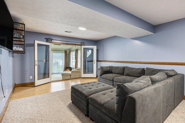 living area with baseboards, french doors, and wood finished floors