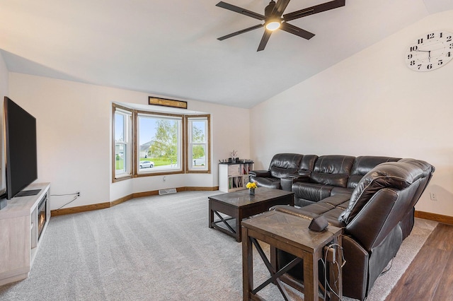 living area with baseboards, a ceiling fan, vaulted ceiling, and wood finished floors