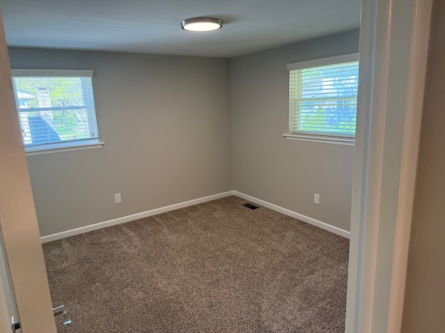 spare room featuring plenty of natural light, carpet, and baseboards