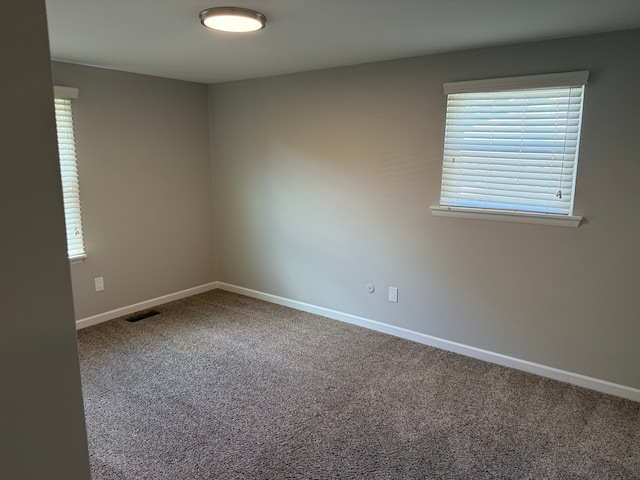 spare room featuring carpet floors and baseboards
