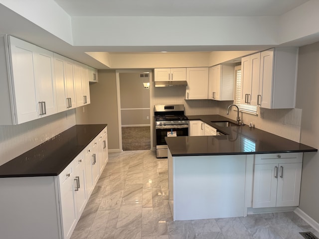 kitchen with stainless steel range with gas stovetop, a sink, under cabinet range hood, and dark countertops