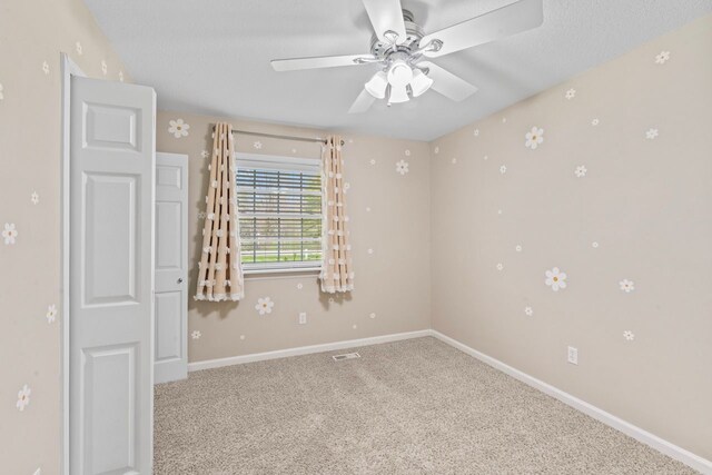 carpeted empty room featuring a ceiling fan and baseboards