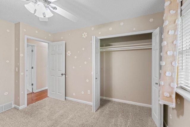 unfurnished bedroom with carpet, a closet, baseboards, and ceiling fan