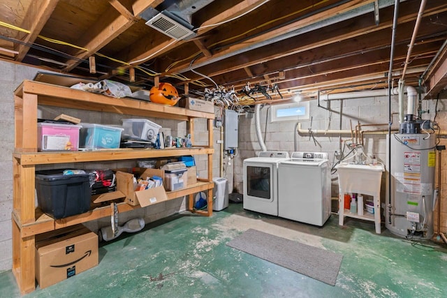 basement with gas water heater, washer and clothes dryer, electric panel, and a sink