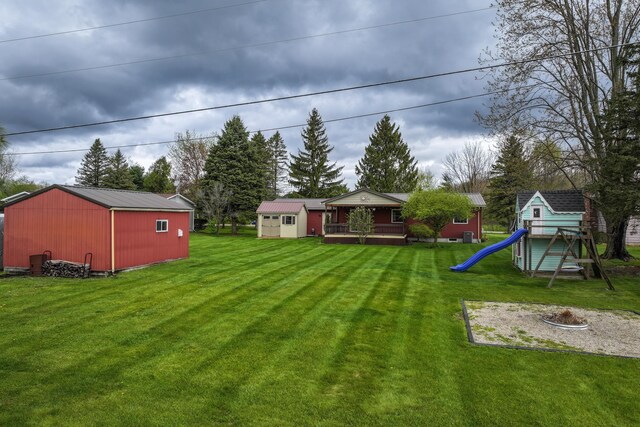 view of green lawn with a playground, an outdoor structure, and a shed