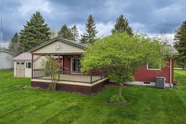 back of property featuring central AC unit, a lawn, and metal roof