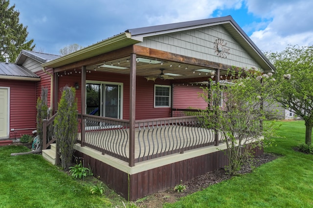 rear view of property with a ceiling fan, a yard, metal roof, and a wooden deck