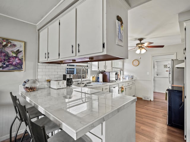 24730 Ridgedale St, Oak Park, MI 48237 - kitchen featuring white cabinetry, a sink, a peninsula, light countertops, and ceiling fan