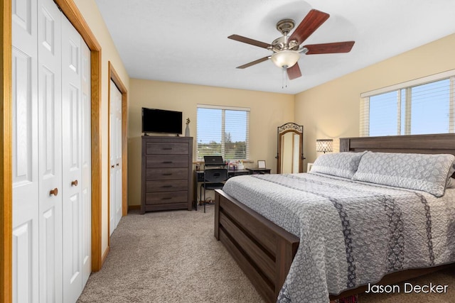 bedroom featuring light colored carpet, ceiling fan, and a desk