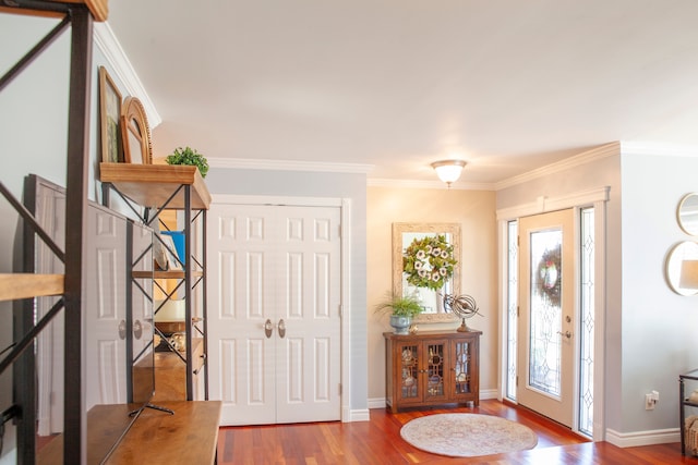 foyer with wood finished floors, crown molding, and baseboards