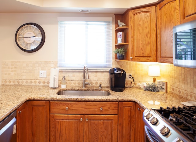 kitchen with stainless steel appliances, a sink, tasteful backsplash, and light stone countertops