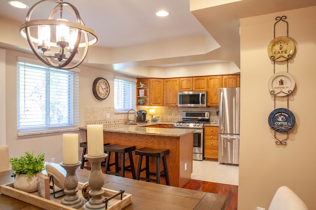 kitchen with stainless steel appliances, brown cabinets, a chandelier, a peninsula, and open shelves