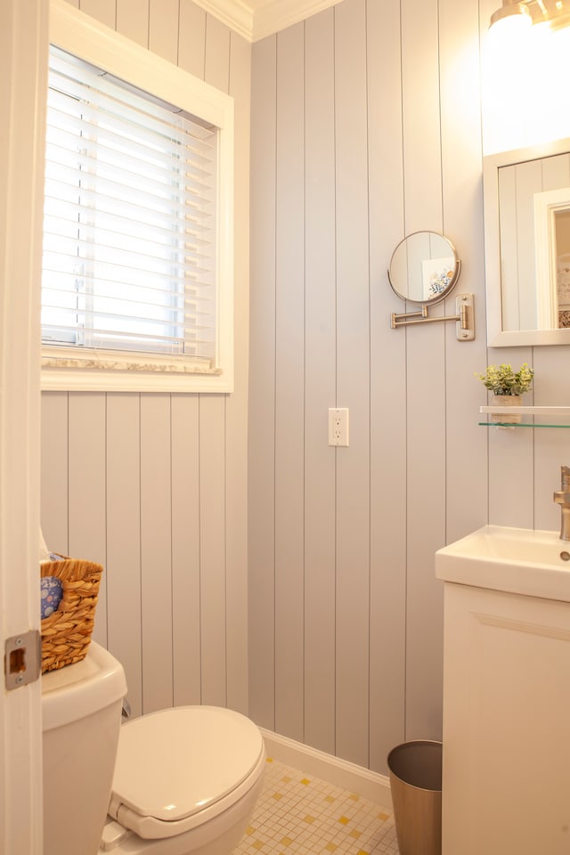 half bath featuring toilet, a decorative wall, and vanity