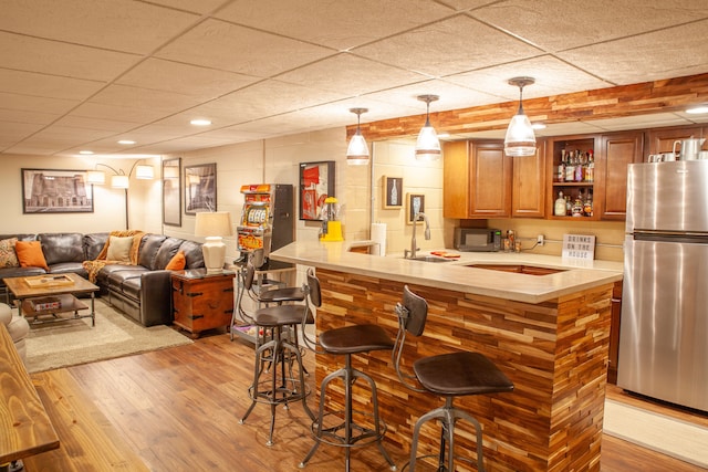 indoor wet bar with stainless steel appliances, wood finished floors, and hanging light fixtures