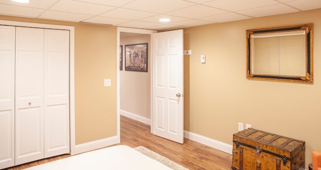 bedroom with light wood-type flooring, a paneled ceiling, baseboards, a closet, and recessed lighting