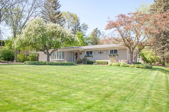 view of front facade featuring a front lawn, brick siding, and a garage