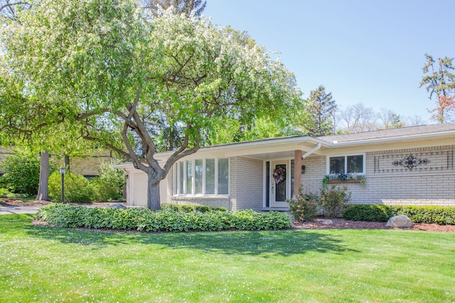 ranch-style home with brick siding, a garage, and a front yard