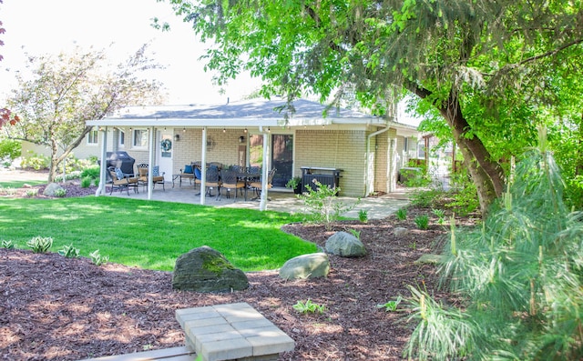 back of property with a patio, a yard, and brick siding
