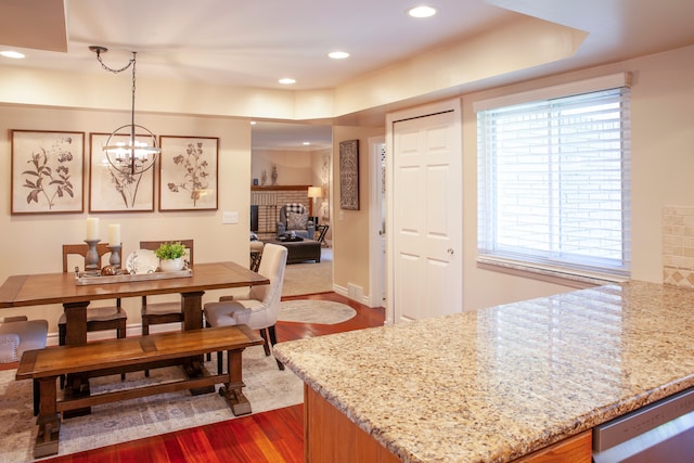 dining space featuring dark wood-style floors, a fireplace, recessed lighting, and a chandelier
