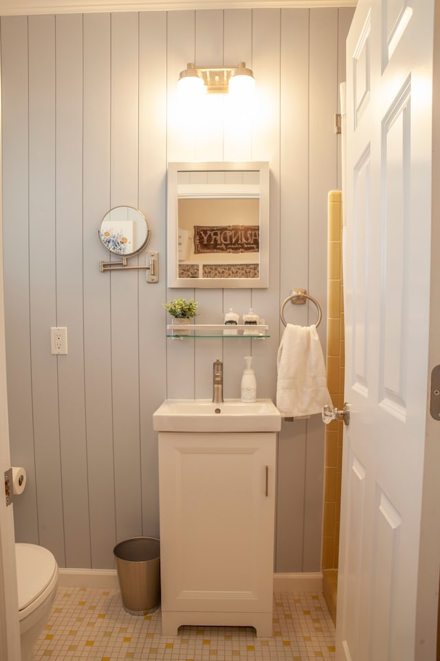 bathroom featuring toilet, a sink, tile patterned flooring, and a decorative wall