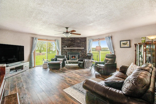 living room featuring a textured ceiling, a ceiling fan, healthy amount of natural light, hardwood / wood-style floors, and a textured wall