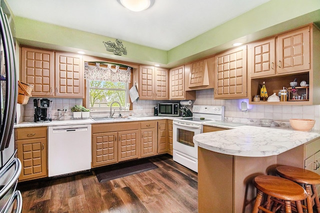 kitchen with appliances with stainless steel finishes, a sink, light brown cabinetry, a peninsula, and light countertops