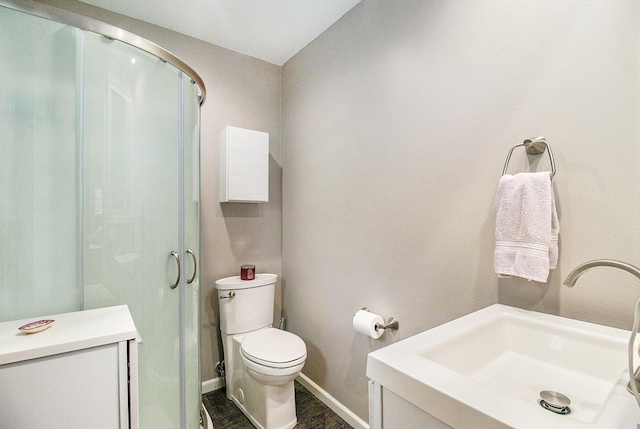 bathroom featuring toilet, baseboards, and a shower with door
