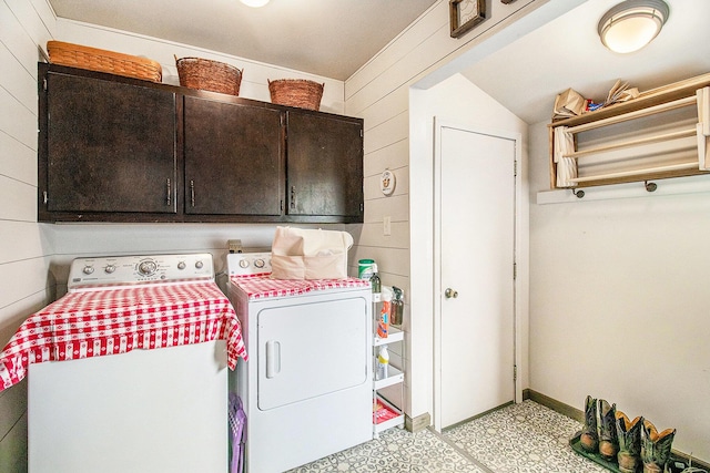 laundry area featuring washing machine and clothes dryer, cabinet space, light floors, wooden walls, and baseboards