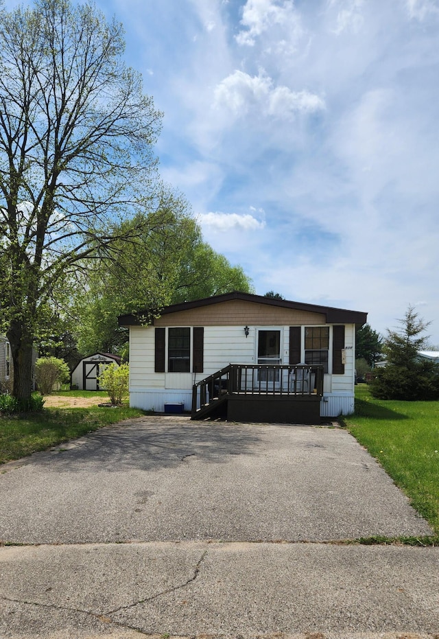 manufactured / mobile home featuring a shed, asphalt driveway, and an outbuilding