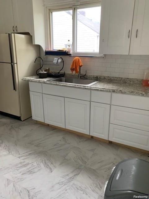 8097 Marlowe St, Detroit, MI 48228 - kitchen featuring freestanding refrigerator, backsplash, and white cabinets