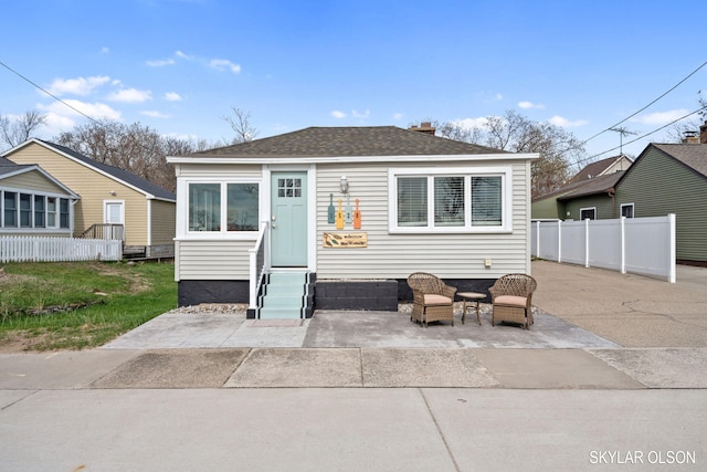 bungalow-style house featuring entry steps, fence, a patio, and roof with shingles