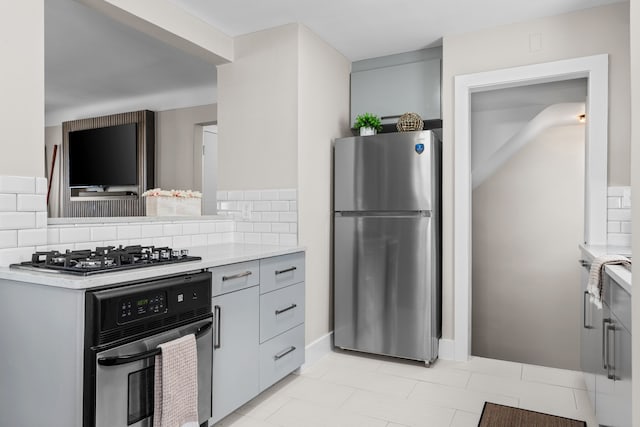 kitchen with appliances with stainless steel finishes, light countertops, decorative backsplash, gray cabinets, and light tile patterned floors