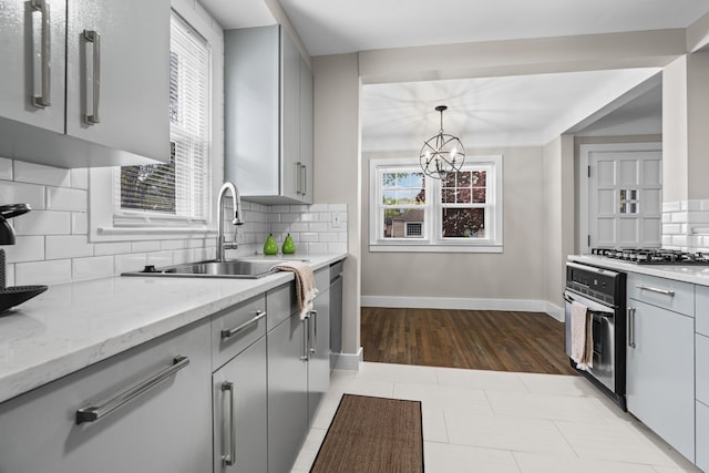 kitchen featuring gray cabinetry, stainless steel appliances, a sink, and plenty of natural light