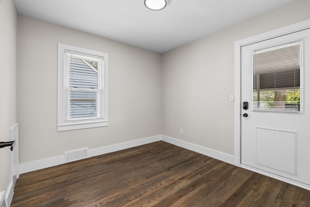 empty room with plenty of natural light, dark wood-style flooring, and baseboards