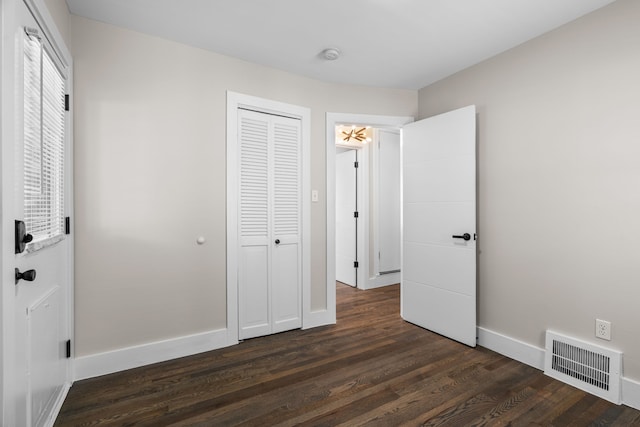 unfurnished bedroom featuring dark wood finished floors, baseboards, and a closet