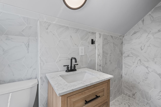 bathroom with vanity, toilet, and tile walls
