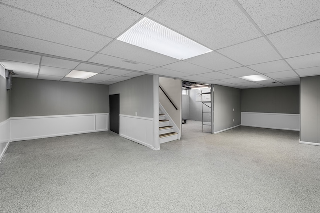 finished below grade area featuring stairway, a paneled ceiling, and baseboards