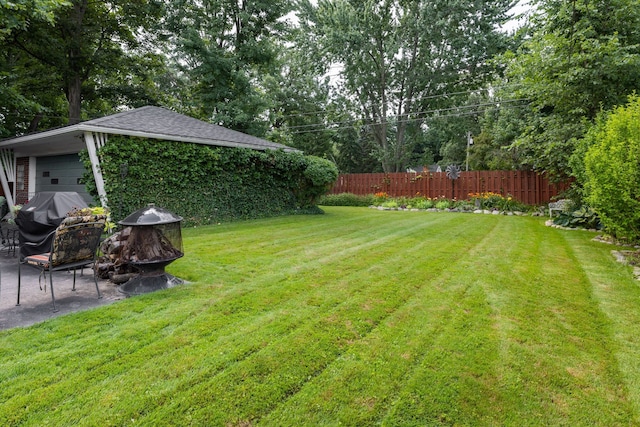 view of yard featuring a fire pit, a patio, and view of scattered trees