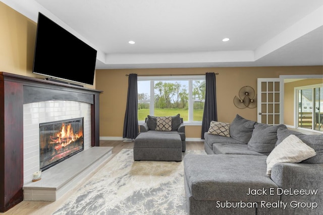 12840 Ridgedale Dr, Allendale, MI 49401 - living room with wood finished floors, a glass covered fireplace, plenty of natural light, a tray ceiling, and recessed lighting
