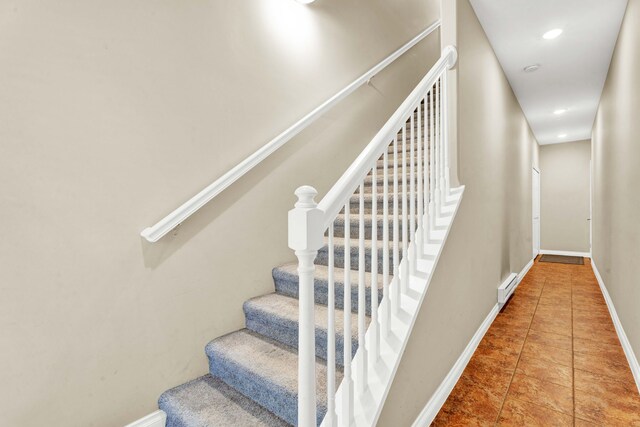stairway featuring baseboard heating, baseboards, tile patterned floors, and recessed lighting