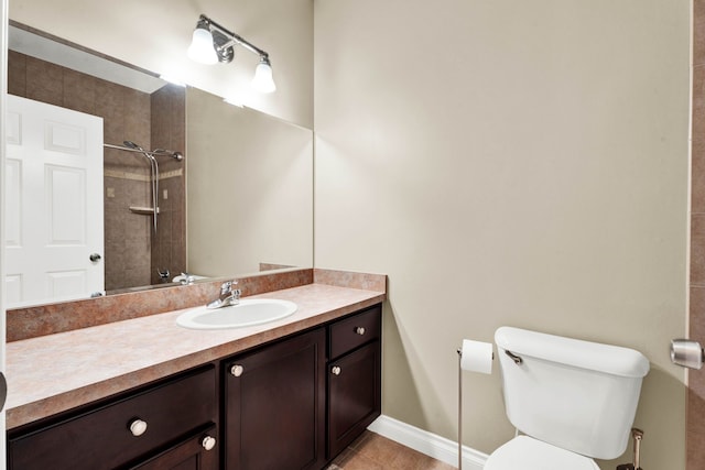 bathroom featuring toilet, vanity, tile patterned floors, and tiled shower