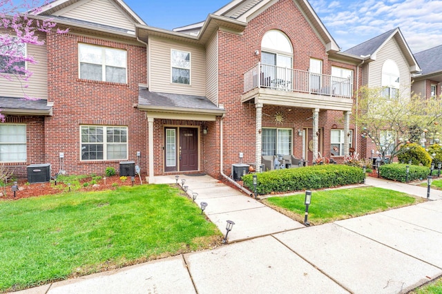 view of property featuring brick siding, a front yard, and cooling unit