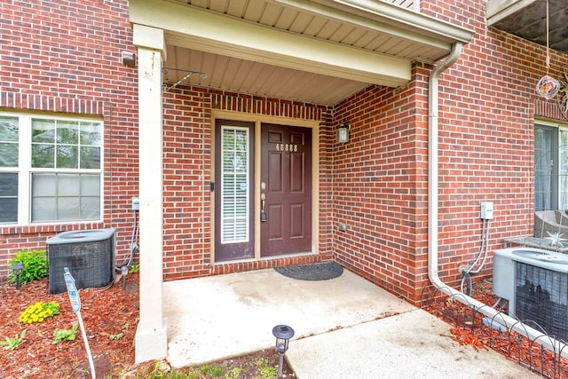 doorway to property with cooling unit and brick siding